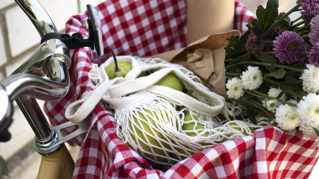 Panier à vélo avec tissu vichy, filet de fruits et fleurs.